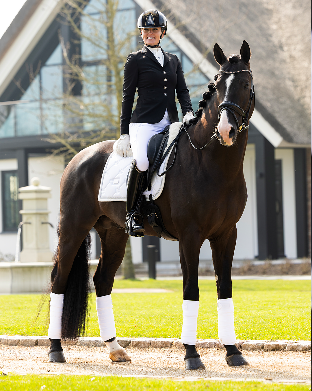 Model on horse wearing JuulC' Black Stardust Women's Show Coat made from sport-tech merino wool 