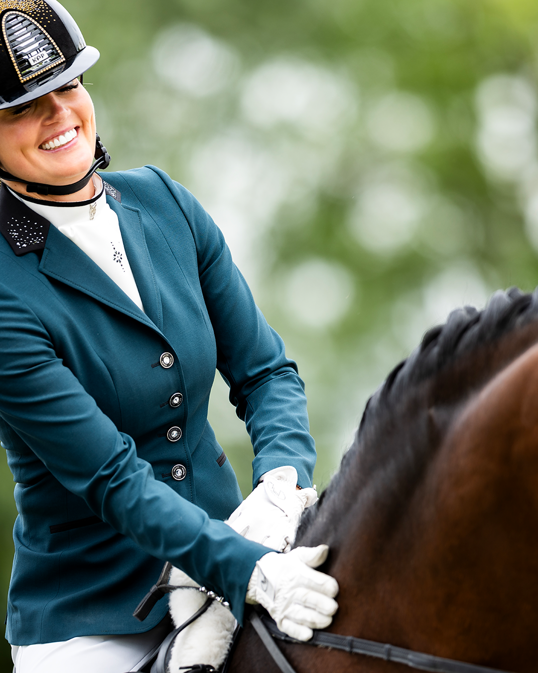 Rider rewarding her horse in the JuulC Emerald Show Coat for women with matching stock-tie